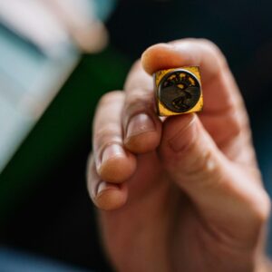 Detailed view of a handcrafted wax seal stamp held in hand, showcasing intricate design.